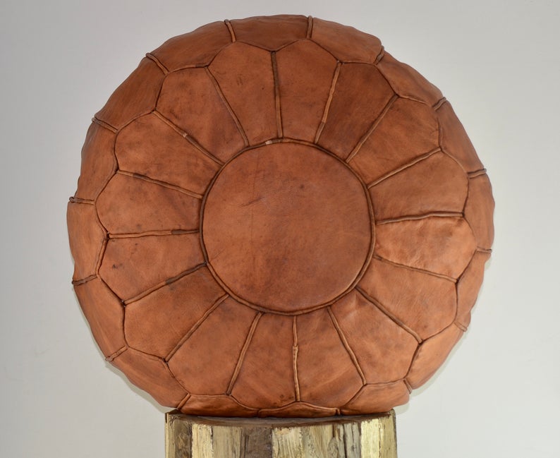 Round Moroccan leather poufs used as a coffee table, handcrafted with durable materials and traditional stitching in natural tones.