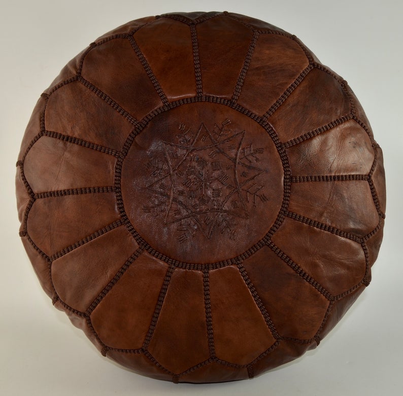 Round Moroccan leather poufs used as a coffee table, handcrafted with durable materials and traditional stitching in natural tones.