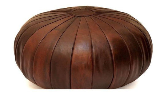 Round Moroccan leather poufs used as a coffee table, handcrafted with durable materials and traditional stitching in natural tones.