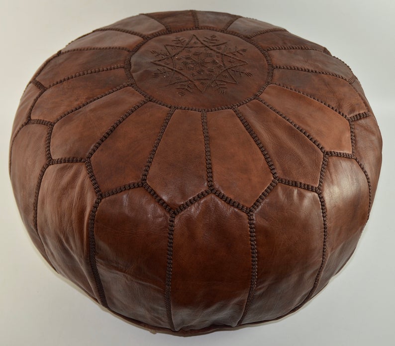 Round Moroccan leather poufs used as a coffee table, handcrafted with durable materials and traditional stitching in natural tones.