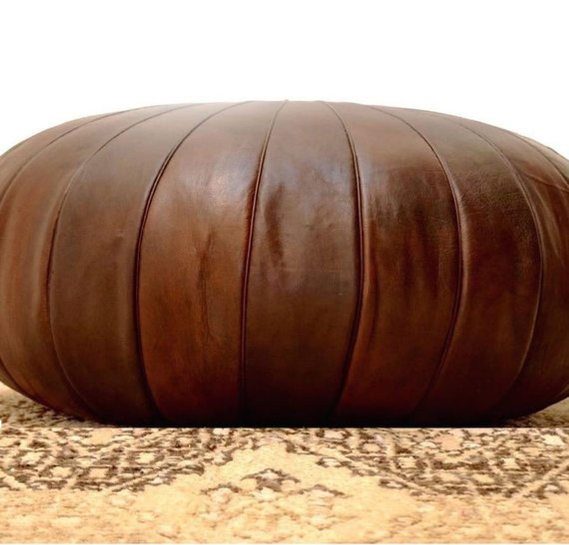 Round Moroccan leather poufs used as a coffee table, handcrafted with durable materials and traditional stitching in natural tones.