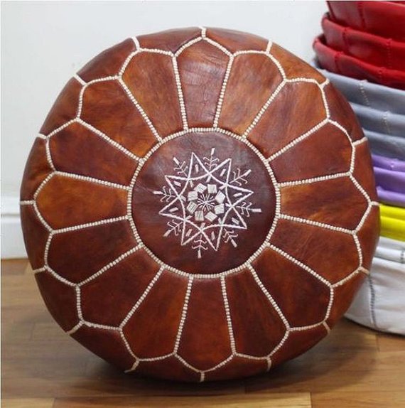 Round Moroccan leather poufs used as a coffee table, handcrafted with durable materials and traditional stitching in natural tones.