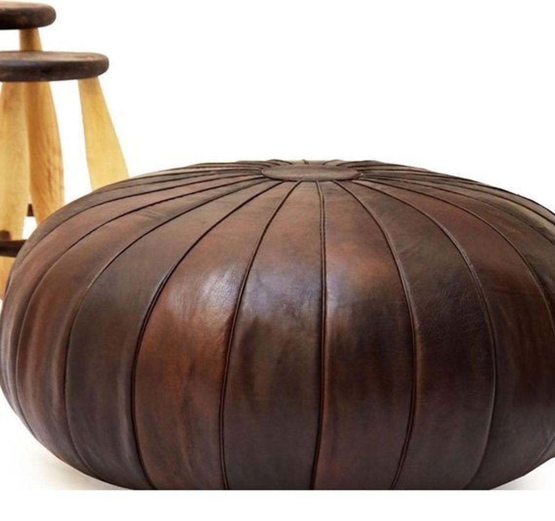 Round Moroccan leather poufs used as a coffee table, handcrafted with durable materials and traditional stitching in natural tones.