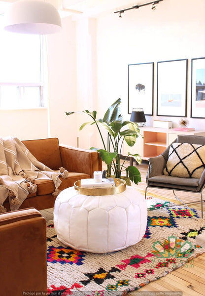 Round Moroccan leather poufs used as a coffee table, handcrafted with durable materials and traditional stitching in natural tones.