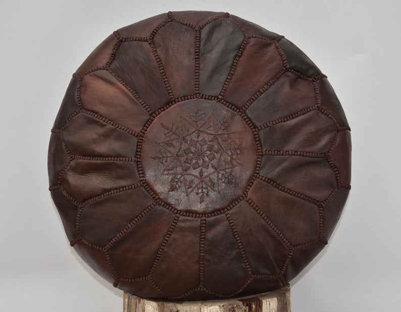 Luxurious brown leather Moroccan pouf ottoman by Moroccancraftdream, used as a footrest or extra seating option.