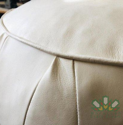 White handmade round Moroccan pouf ottoman in genuine leather, perfect for use as a versatile coffee table or footrest. This Moroccan leather ottoman enhances living room decor with its elegant design and multifunctional use.